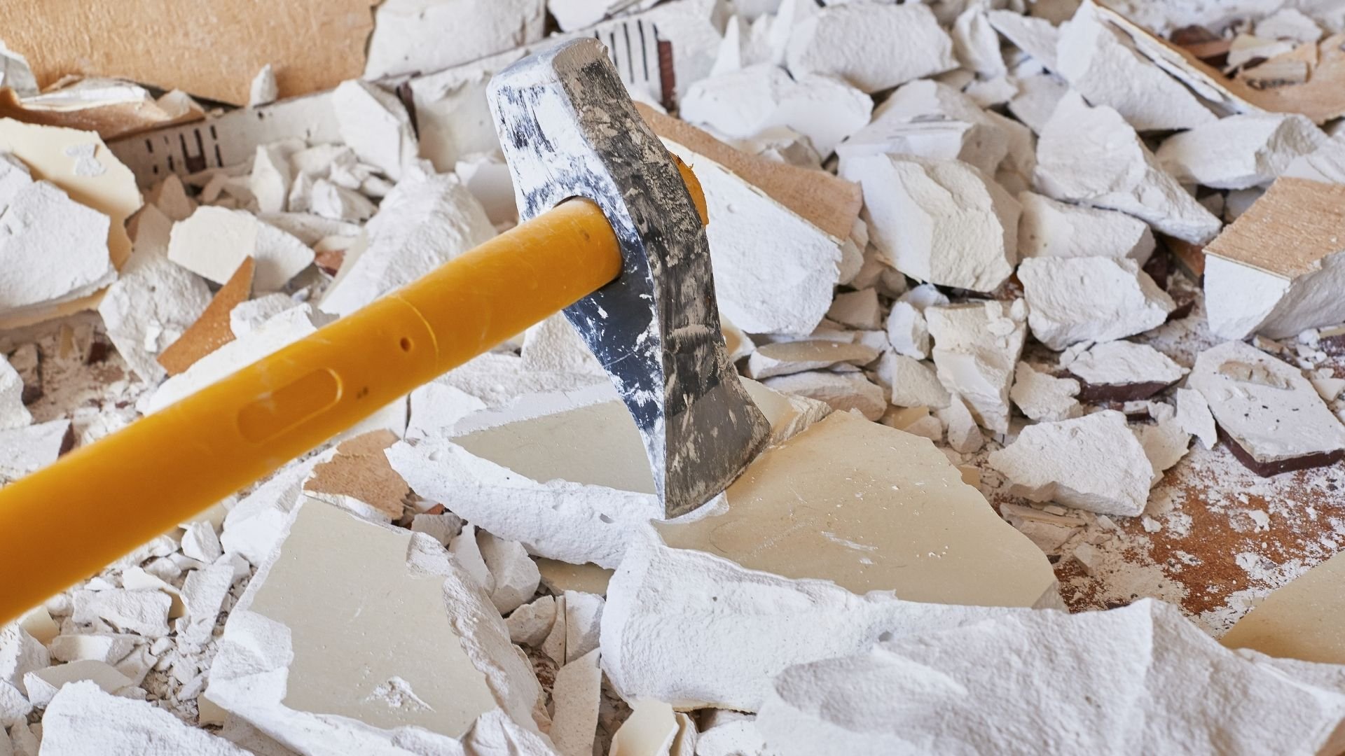 Chisel with yellow handle on white paint chips and debris