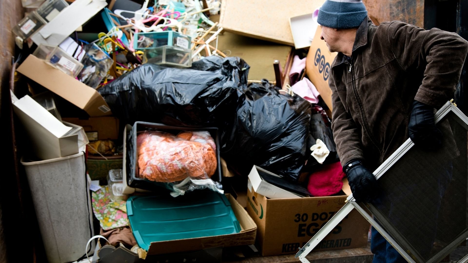 Man sorting through donated items and boxes at a crowded donation center.